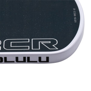 Close-up of a rounded corner featuring a black deck with "CR" and "2 COR 5:21" text above a white side rail with "LULU" printed in black.