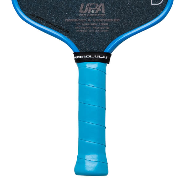 Close-up of the handle and neck of a pickleball paddle, showing a blue grip and the word "HONOLULU" on a black band.