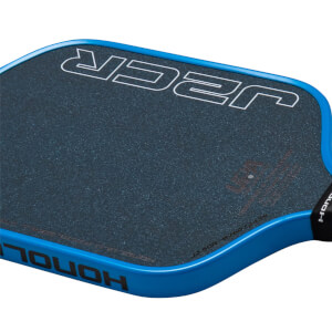 Corner view of a blue pickleball paddle with a textured dark blue grip and white "JCR" logo.