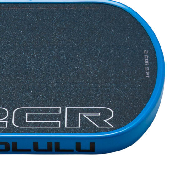 Corner view of a blue board with black speckled grip tape and white lettering "2 COR 5:21".