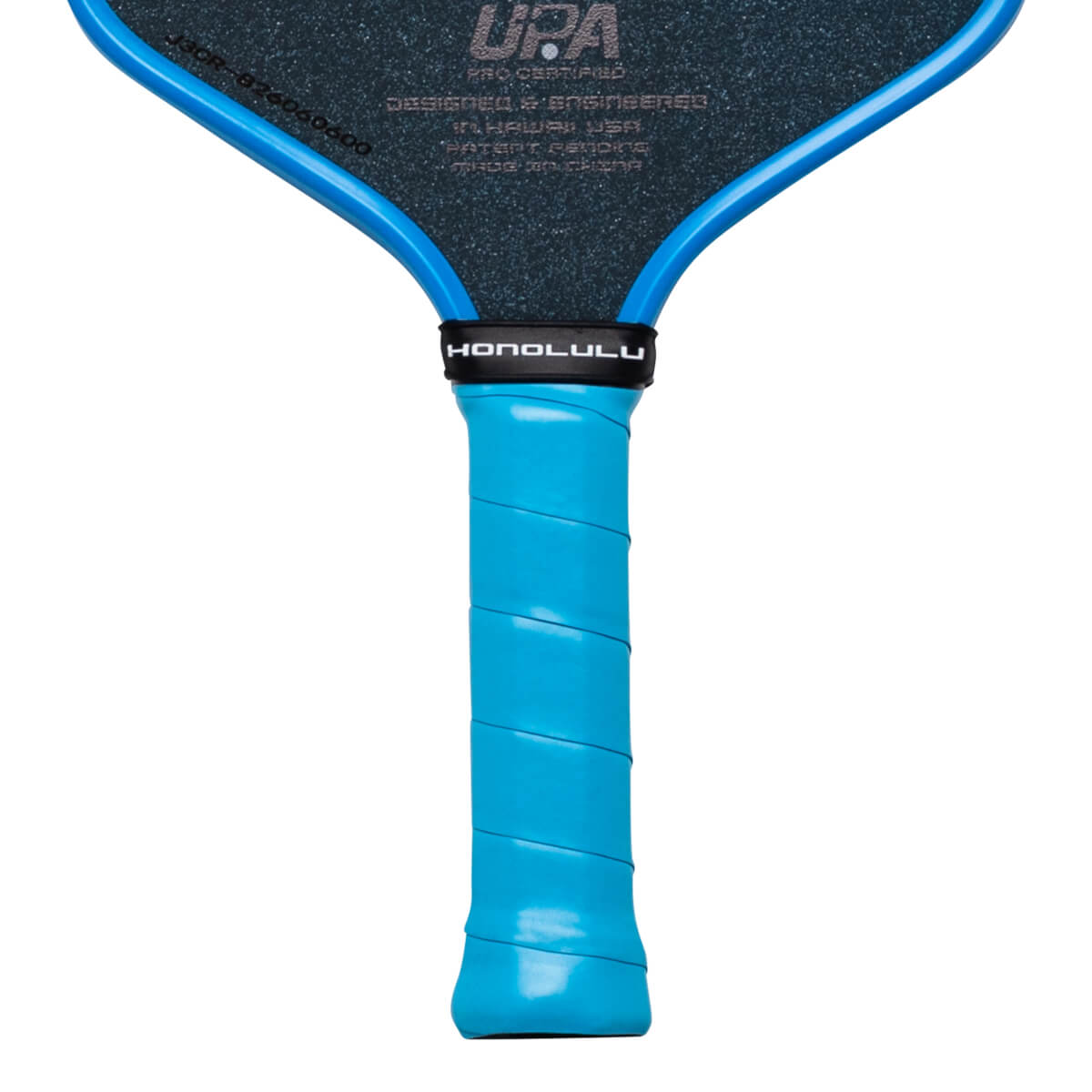 Close-up of the handle and lower head of a pickleball paddle, showing the blue grip, "HONOLULU" text, and "UPA" logo.