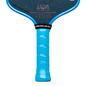 Close-up of a pickleball paddle showing the blue grip, "HONOLULU" text on a black band, and "UPA" logo.