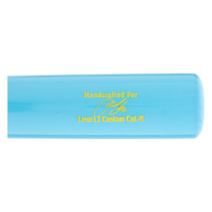 Close-up side view of a light blue baseball bat with yellow Handcrafted For text, a signature graphic, and LINDY12 Custom Cut-M printed on it.
