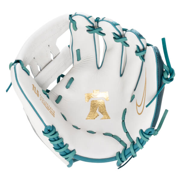 Top-down view of a white baseball glove with teal lacing, a gold Nike swoosh, and a gold Liberty Bell logo.