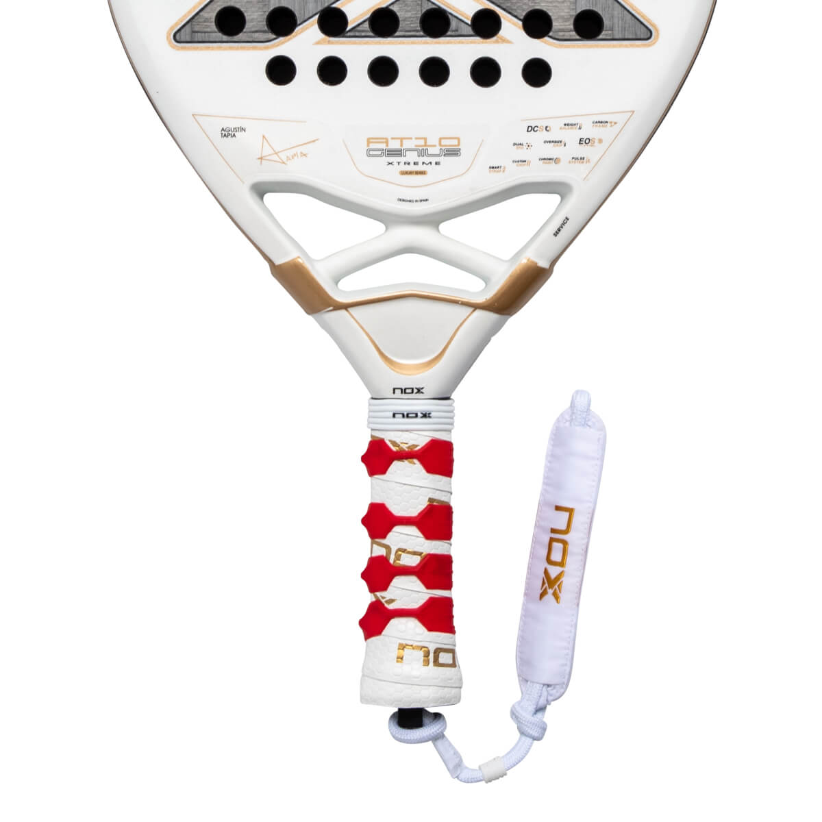 Close-up of the lower white racket face and handle featuring gold "AT10 GENIUS" branding, a red patterned grip, and a white wrist strap with gold "NOX" lettering.
