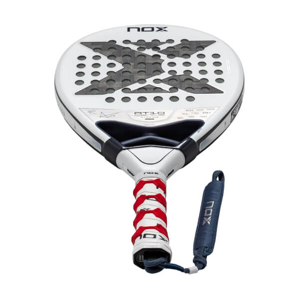 Front view of a white Nox AT10 Genius Xtreme padel racket featuring a large gray X on the face, a red and white textured grip, and a blue NOX-branded wrist strap.