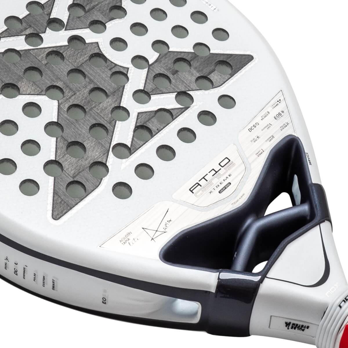 Close-up of a white NOX padel racket face showing the "AT10 GENIUS XTREME" text, a carbon fiber star pattern with circular holes, and a black aerodynamic bridge.