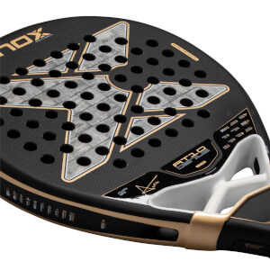 Angled close-up of the Nox AT10 Genius padel racket head featuring a black honeycomb face, a large gray X logo, and gold "AT10 GENIUS" and "AGUSTÍN TAPIA" branding.