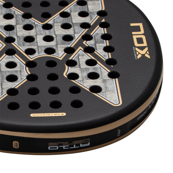 Close-up of the racket face showing the gold NOX logo, 18K Alum carbon fiber weave, and AT10 GENIUS branding on the gold and black side frame.