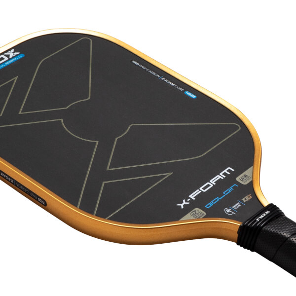 Angled close-up of the Nox X-Foam Goldin pickleball paddle featuring a black T700 raw carbon face with gold edges and prominent "X-FOAM GOLDIN" branding.