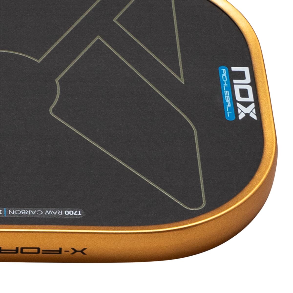 Close-up corner view showing the textured black surface with gold line graphics, a gold edge guard, and visible NOX PICKLEBALL and T700 RAW CARBON text.