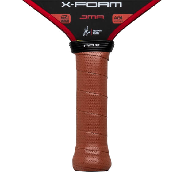Close-up of the brown perforated handle and black neck featuring the NOX logo, with X-FOAM and JMA text visible on the black and red lower face of the paddle.