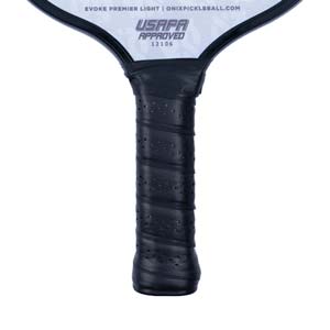 Close-up of a black pickleball paddle grip with perforated texture and USAPA approved stamp.