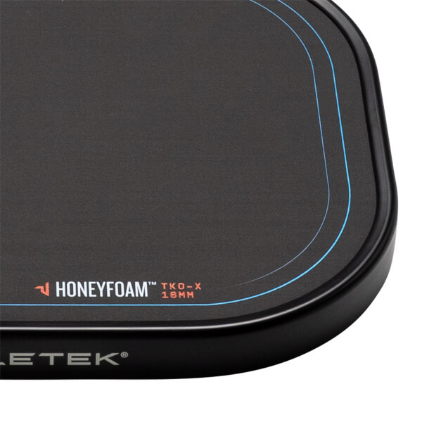 Corner view of a black pickleball paddle with Honeyfoam™ TKO-X 16MM branding and blue accent lines.