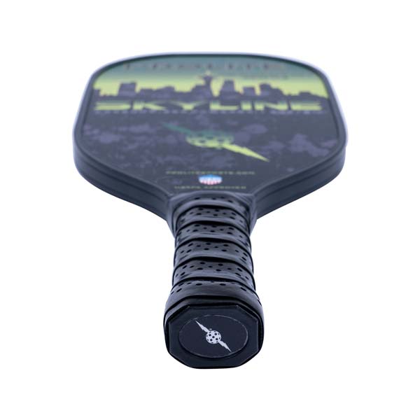 Top-down view of a black pickleball paddle with a skyline graphic and perforated grip.