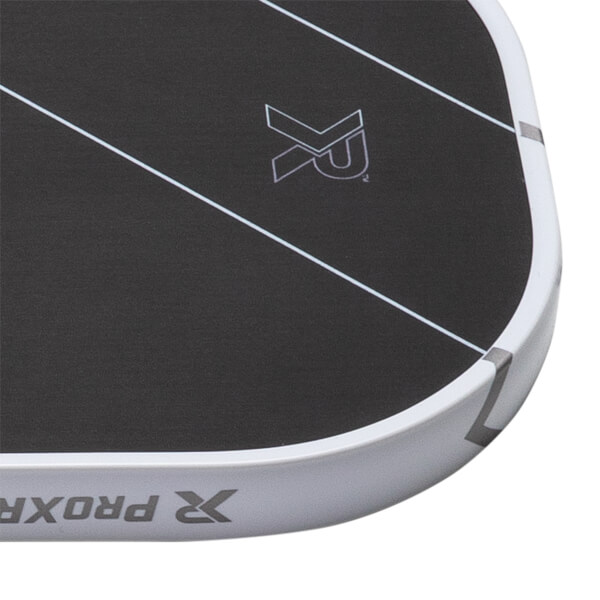 Close-up of black pickleball paddle corner with white diagonal lines, XR logo, and white edge guard with PROXR text.