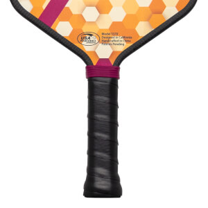 Close-up of the handle and lower paddle face, showing a black grip, purple band, and honeycomb pattern with "USA Pickleball Approved" logo.