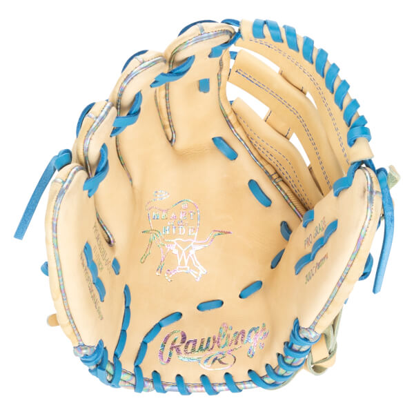 Top-down view of a tan baseball glove with blue lacing and iridescent accents, featuring "Rawlings" and "Heart of the Hide" logos.