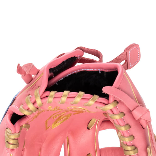 Close-up of a pink baseball glove showing gold lacing and gold leaf accents.