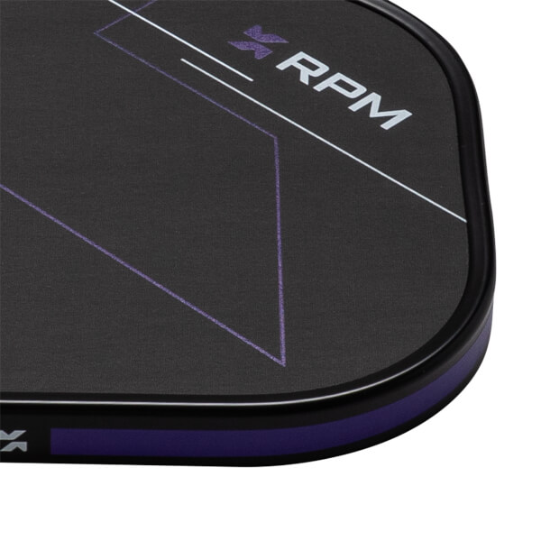 Close-up corner view of a black textured paddle face featuring purple geometric lines, a purple edge guard, and the word "RPM" in bold white letters.
