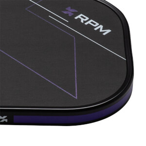 Close-up corner view of a black textured paddle face featuring purple geometric lines, a purple edge guard, and the word "RPM" in bold white letters.