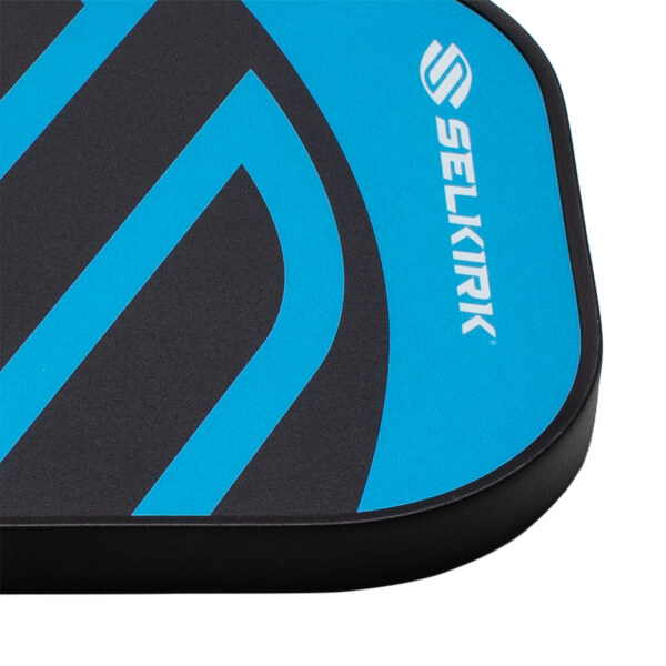 Close-up of the top right corner of a black and blue pickleball paddle, showing a black edge guard, abstract blue lines, and white Selkirk logo.