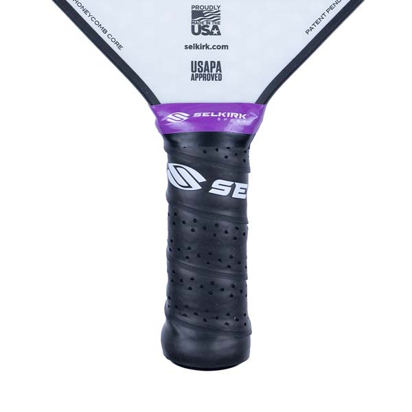 Close-up of a black pickleball paddle grip with purple Selkirk branding and USAPA approved logo.