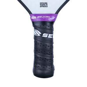 Close-up of a black pickleball paddle grip with purple Selkirk Sport branding and USAPA Approved text.