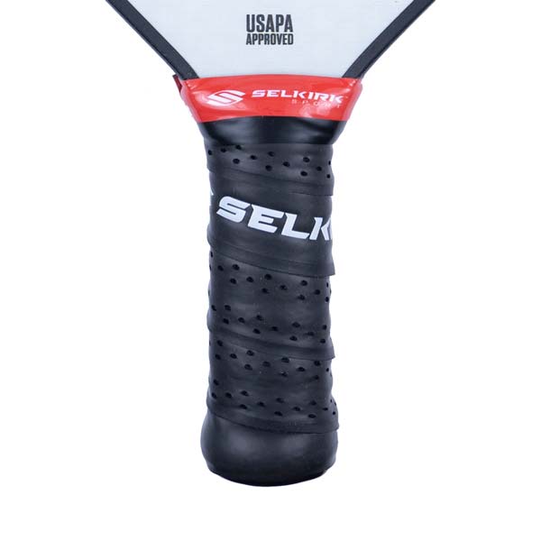 Close-up of a black pickleball paddle grip with white SELKIRK text and red Selkirk branding.