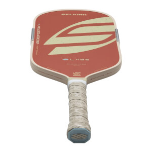 Top-down view of a Selkirk pickleball paddle with a red and cream design, "PROJECT BOOSTIK" text, and a textured grip.