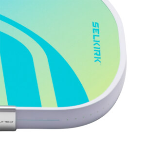 Corner view of a pickleball paddle with a gradient of teal and lime green, featuring the "SELKIRK" logo and a silver edge band.