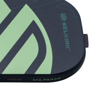 Close-up of a dark blue pickleball paddle with light green geometric design, Selkirk logo, and Invikta text on the edge.