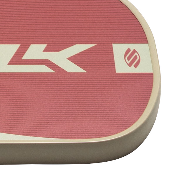 Close-up of a pink paddle with a cream stripe, a stylized "LK" logo, and a circular logo.