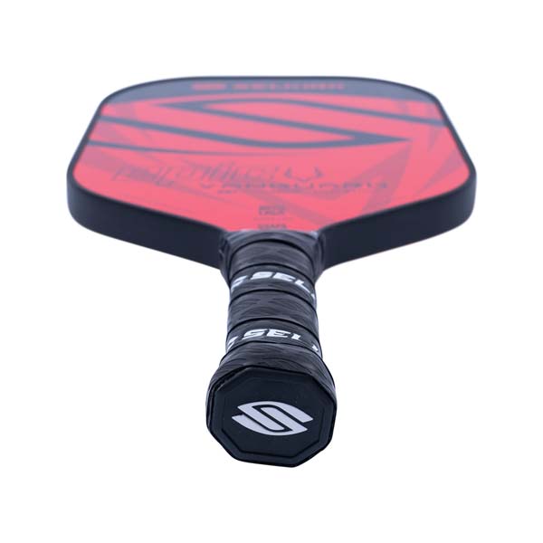 Top-down view of a red pickleball paddle with black geometric accents and a black grip with Selkirk branding.