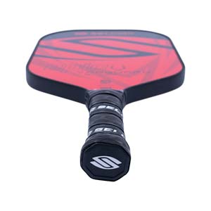 Top-down view of a red pickleball paddle with black geometric accents and a black grip with Selkirk branding.