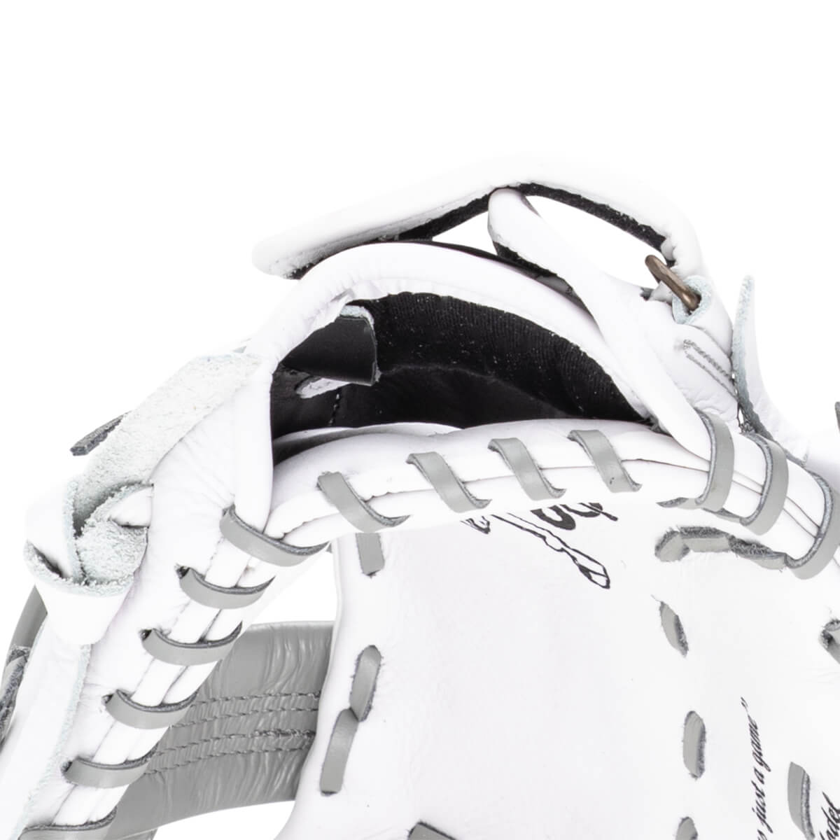 Close-up of a white baseball glove showing grey lacing, a metal ring, and the words "just a game".