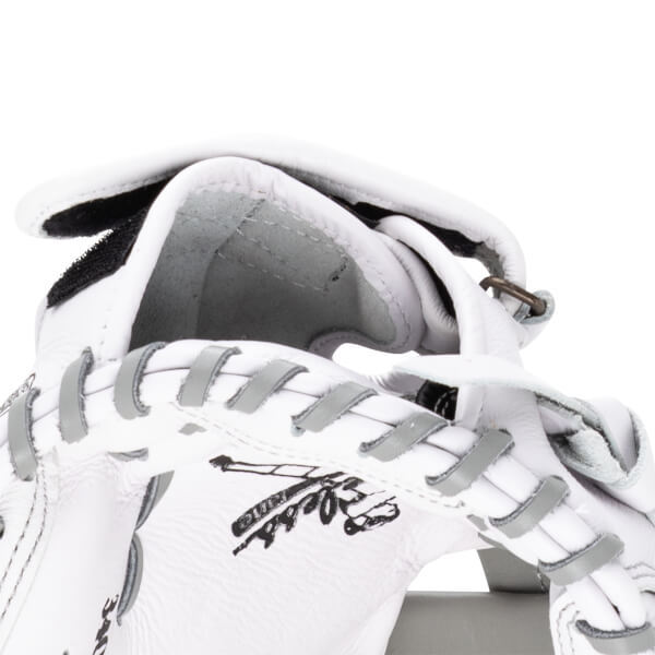 Close-up of a white baseball glove showing grey lacing and a black logo.