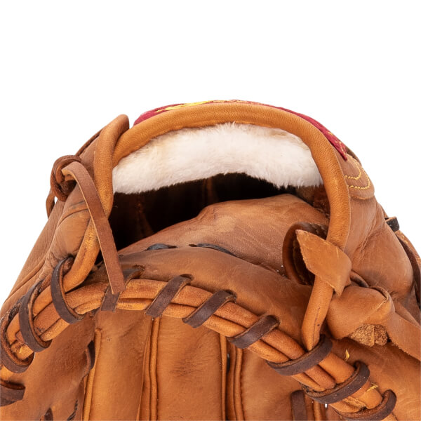 Close-up of a brown baseball glove showing white fluffy wrist padding, brown leather lacing, and red stitching.
