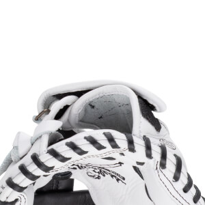Close-up of the white leather mitt's wrist opening and interior padding with black laces and a partial Shoeless Jane logo graphic.
