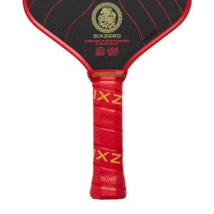 Close-up of a black pickleball paddle with a red perforated grip, gold SIXZERO branding, and a gold dragon emblem.