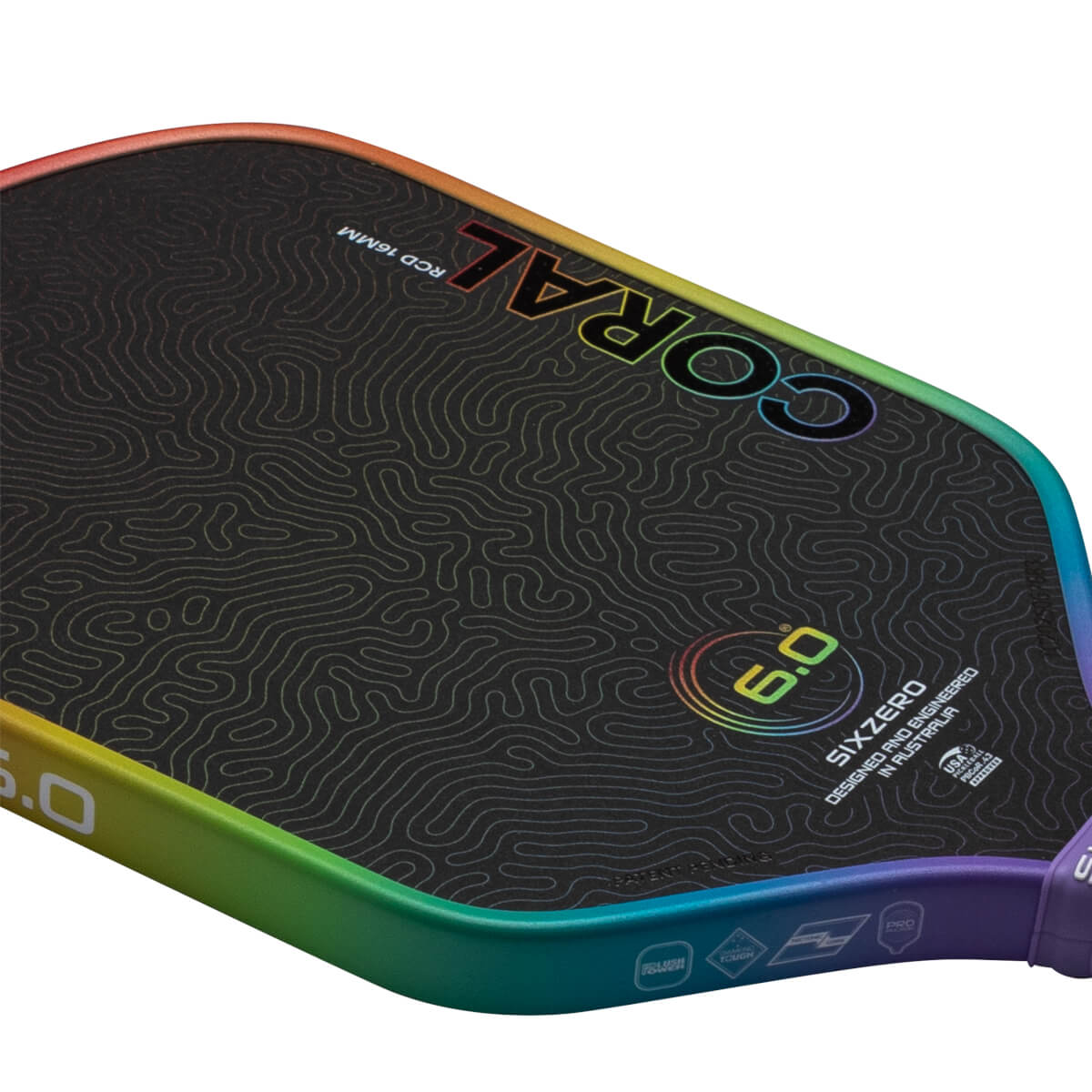 Top-down view of a pickleball paddle with a black textured surface, rainbow-colored edge, and "CORAL 6.0" text.