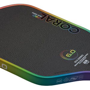 Corner view of a black surfboard with a rainbow-colored edge, featuring "CORAL PRO" text and a "6.0" graphic.