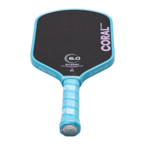 Angled front view of a Six Zero Coral pickleball paddle featuring a light blue frame and grip, a black topographic patterned face, and pink "CORAL" lettering.
