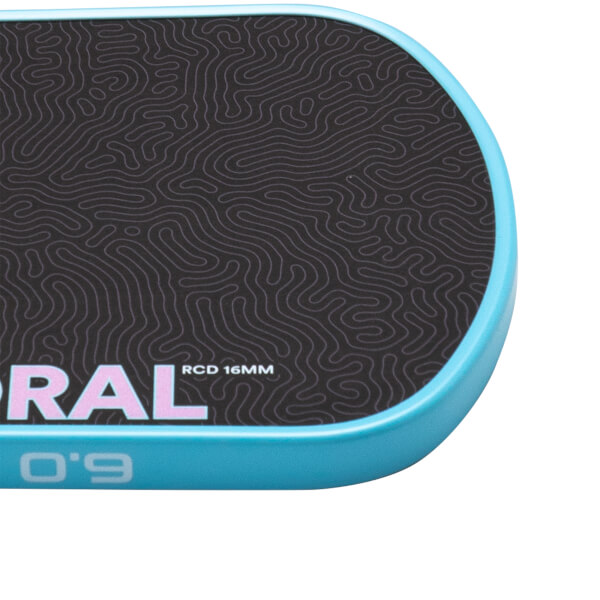 Close-up corner view of a paddle featuring a black topographical pattern, a light blue edge guard showing "6.0", and the text "RAL" and "RCD 16MM" on the face.