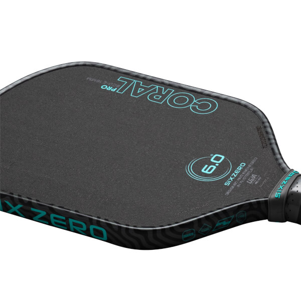 Corner view of a black pickleball paddle with "CORAL PRO" and "SIX ZERO" in teal.