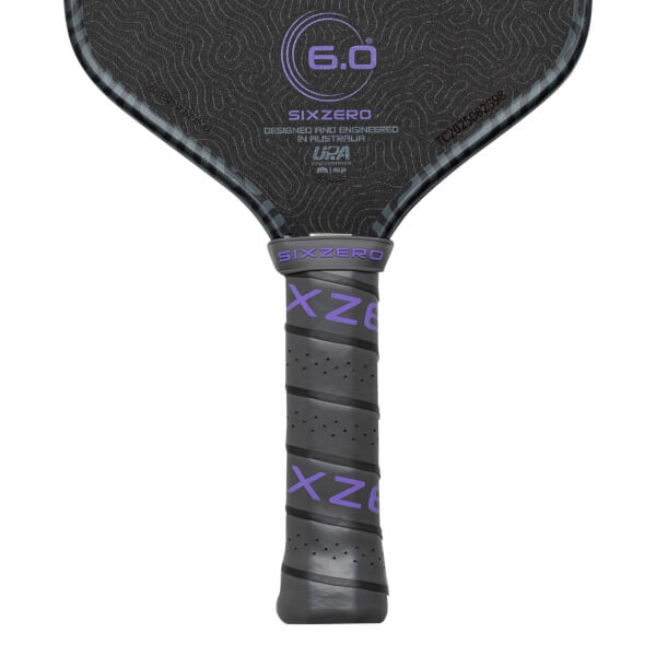 Close-up of a pickleball paddle grip showing purple "SIXZERO" text and a textured surface.