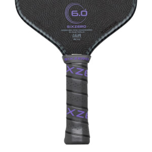 Close-up of a pickleball paddle grip showing purple "SIXZERO" text and a textured surface.