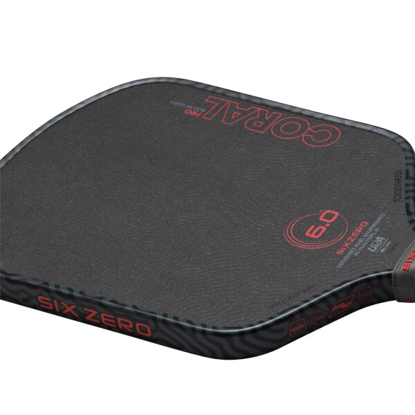 Close-up of a pickleball paddle showing the "SIX ZERO" logo, "CORAL PRO" text, and a "6.0" rating.