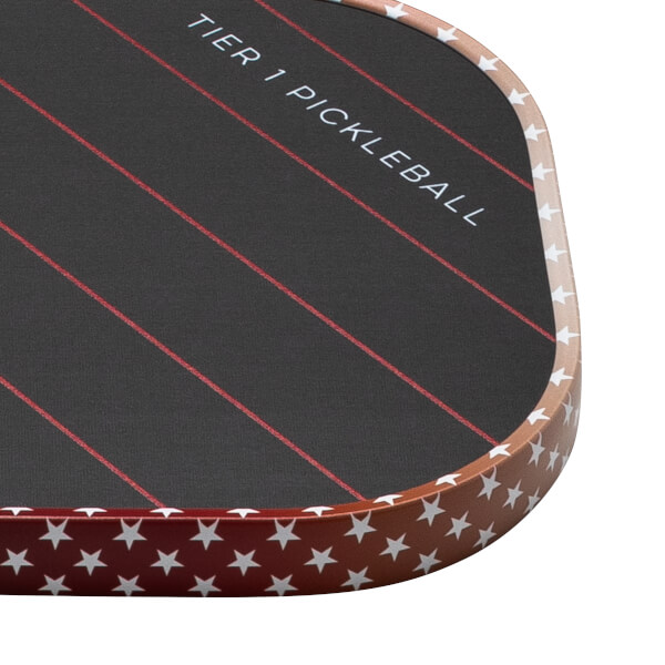 Corner view of a pickleball paddle with "TIER 1 PICKLEBALL" text, red stripes, and a star pattern on the edge.