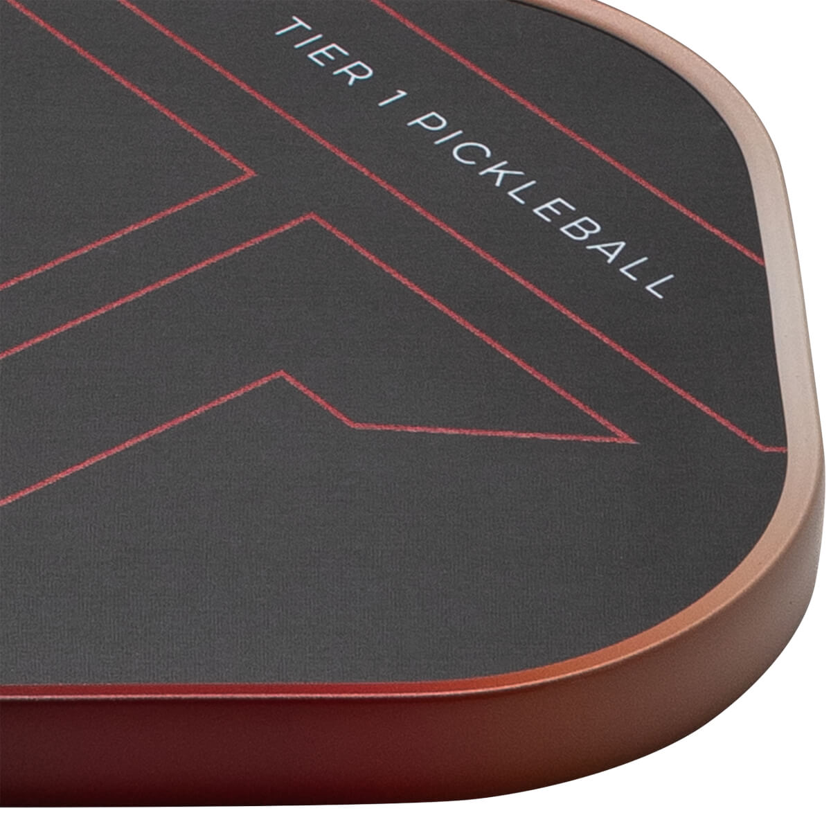 Close-up of a pickleball paddle corner showing red geometric lines and "TIER 1 PICKLEBALL" text on a dark surface.